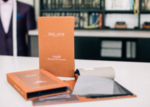 Sport coat fabric swatch books on a fabric bar at Balani Custom Suits.